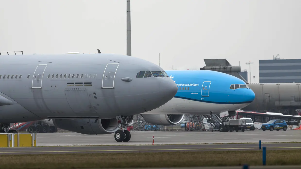 et geparkeerde tank- en transportvliegtuig, met daarachter een geparkeerd passagiersvliegtuig van KLM, met de kenmerkende blauwe kleur. 