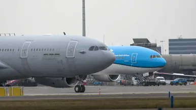 et geparkeerde tank- en transportvliegtuig, met daarachter een geparkeerd passagiersvliegtuig van KLM, met de kenmerkende blauwe kleur. 