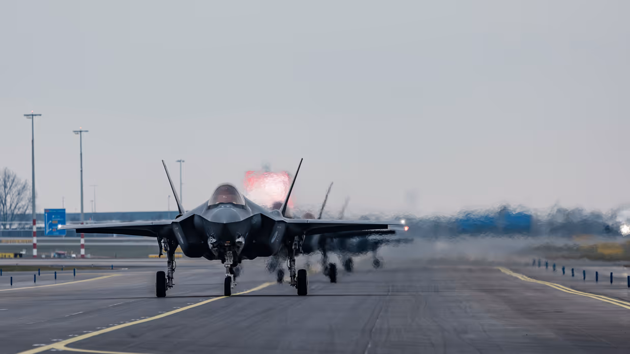 Links F-35’s opgelijnd op de startbaan van Schiphol, rechts: Een tank- en transportvliegtuig A330 MRTT landt op luchthaven Schiphol. De wielen raken net de grond wanneer de foto wordt gemaakt, waardoor er een klein rookwolkje ontstaat.  
