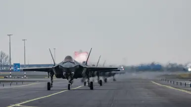 Links F-35’s opgelijnd op de startbaan van Schiphol, rechts: Een tank- en transportvliegtuig A330 MRTT landt op luchthaven Schiphol. De wielen raken net de grond wanneer de foto wordt gemaakt, waardoor er een klein rookwolkje ontstaat.  