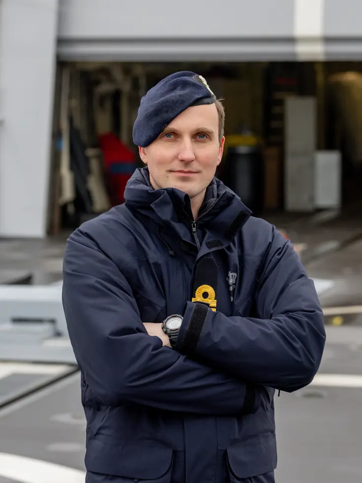 De squadroncommandant in uniform met de handen voor de borst.