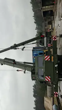 Twee hijskranen naast elkaar hijsen materialen op. 