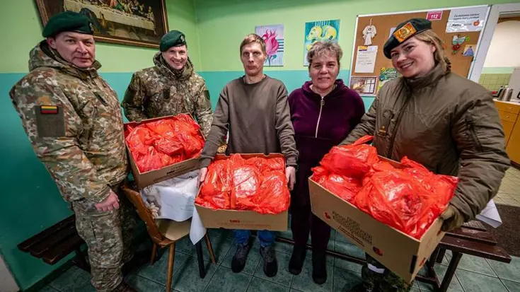 Drie militairen delen voedselpakketten uit aan Litouwers