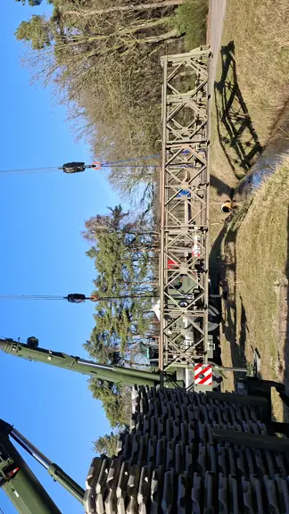 Twee hijskranen naast elkaar hijsen materialen op. 