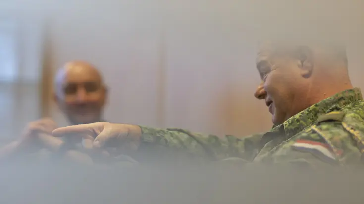 Oud-Luchtmachtadjudant Terry Venhovens spreekt geanimeerd en wijst met zijn wijsvinger. De nieuwe Luchtmachtadjudant Johan de Rooij kijkt Venhovens op de achtergrond aan.    