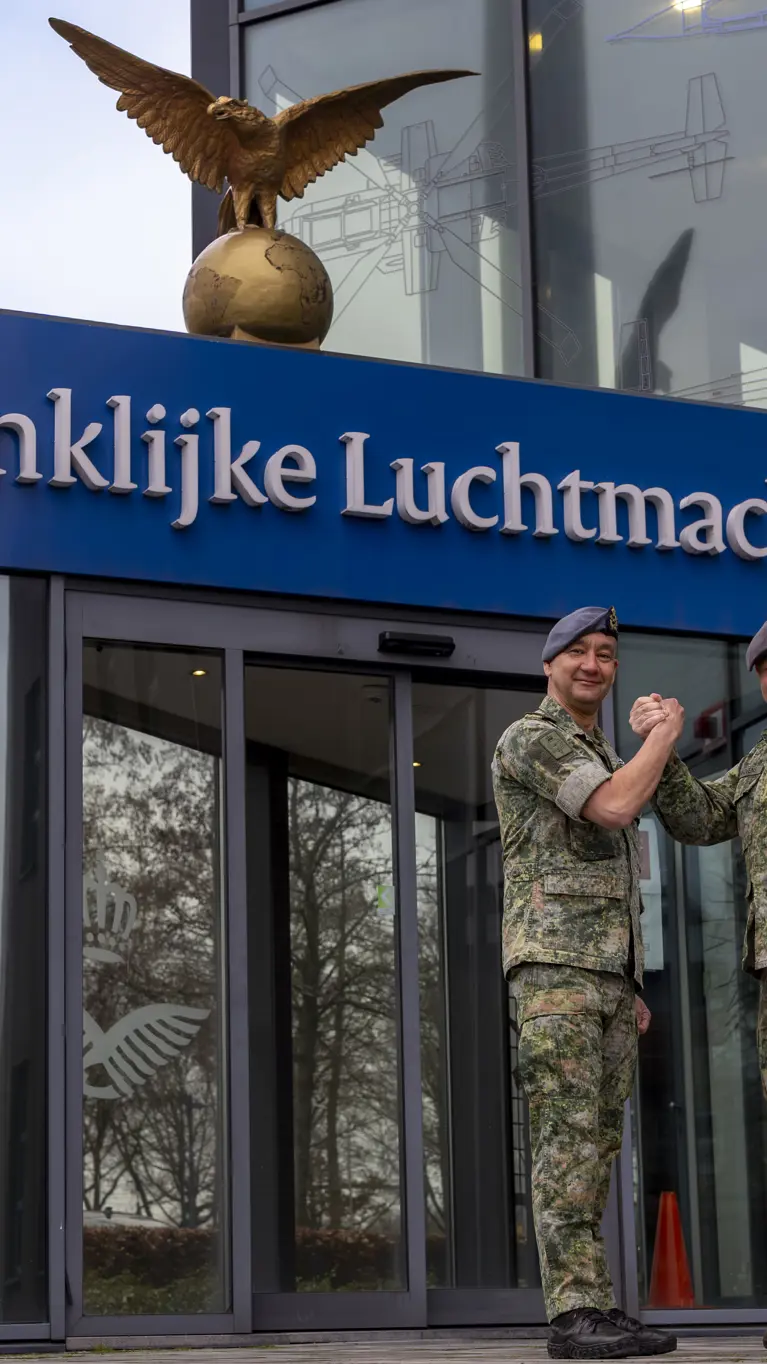  Luchtmachtadjudanten Terry Venhovens en Johan de Rooij schudden elkaar de hand voor de ingang van de Luchtmachttoren in Breda.