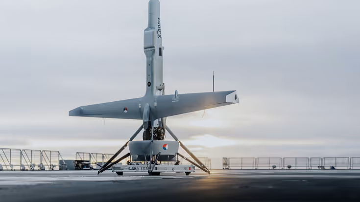 Een V-BAT drone staat naar boven gericht op het dek van een schip.