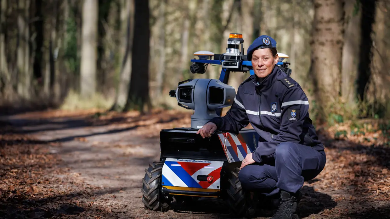 Kolonel Daisy, projectmanager innovatie bij DevOps, poseert bij de Roboguard in het bos.