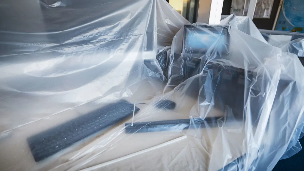 Vier foto’s van werkzaamheden. Naast een kantoorruimte met afgedekte bureaus, laptops en toetsenborden gaat het om een kabel die uit het plafond hangt. Tot slot het logo van de luchtmacht tegen een muur, daarnaast een afgedekt beeldscherm.