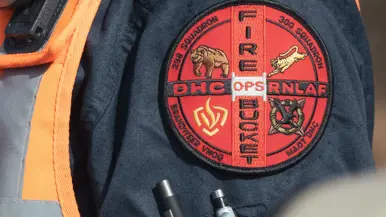 En badge op de mouw van een brandweerman met onder meer de tekst ‘DHC RNLAF – Fire Bucket Ops’.
