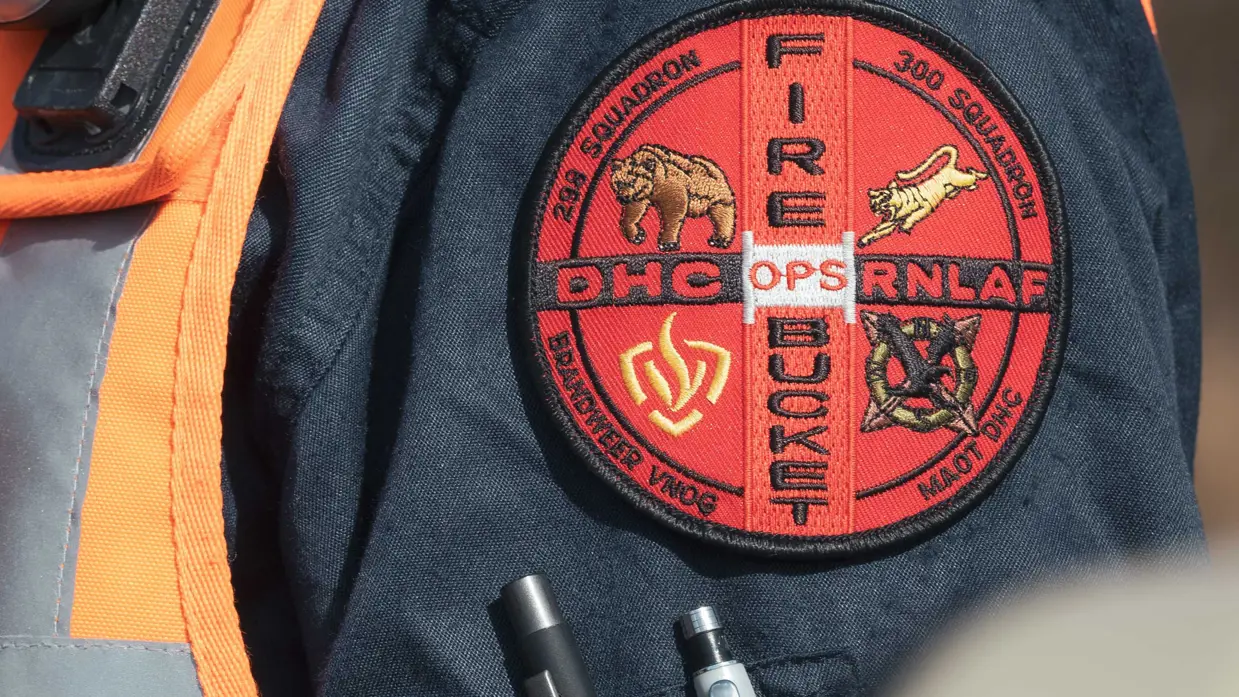 En badge op de mouw van een brandweerman met onder meer de tekst ‘DHC RNLAF – Fire Bucket Ops’.