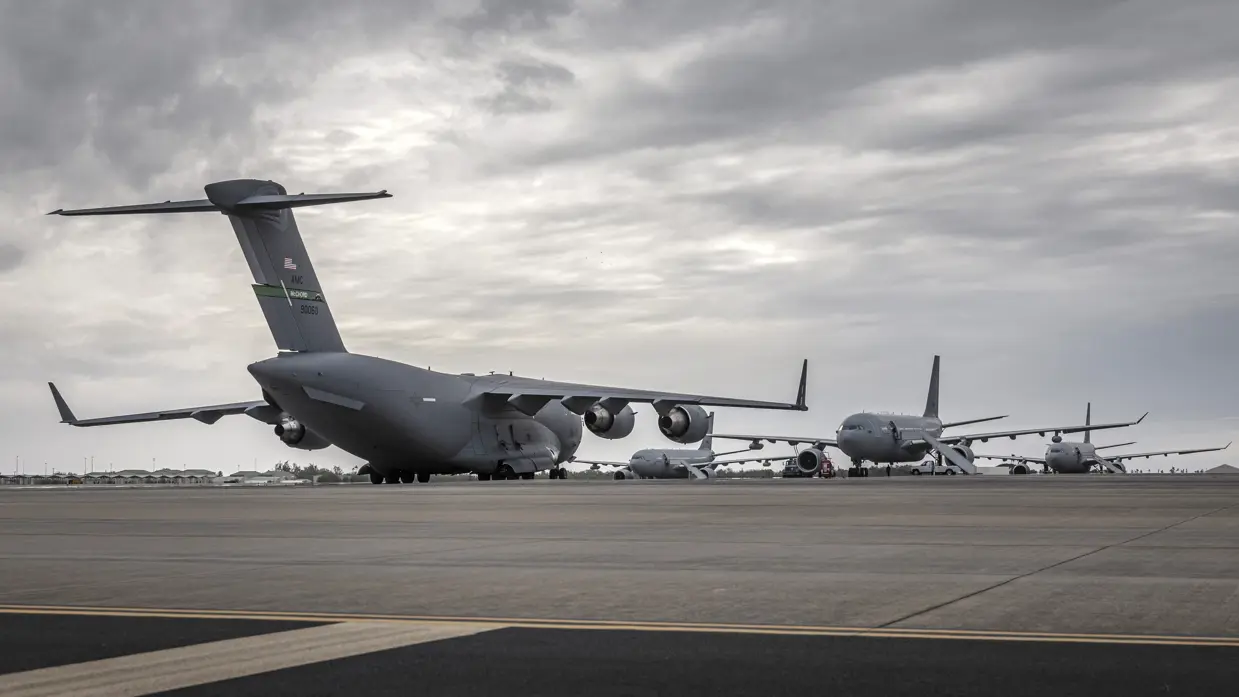 Op een groot platform staat een C-17 transportvliegtuig met de staart naar de camera. In de achtergrond zijn drie A330 MRTT’s te zien