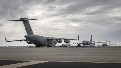 Op een groot platform staat een C-17 transportvliegtuig met de staart naar de camera. In de achtergrond zijn drie A330 MRTT’s te zien