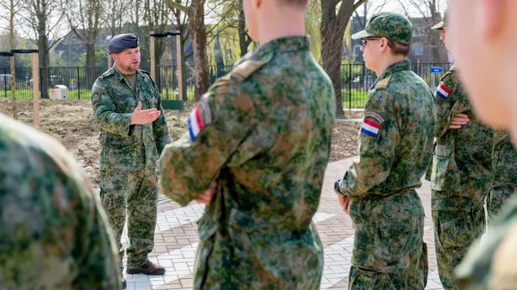 Buiten staat een rijtje jongeren in gevechtspak. Ervoor staat sergeant-majoor Tim Nelissen die hen toespreekt.