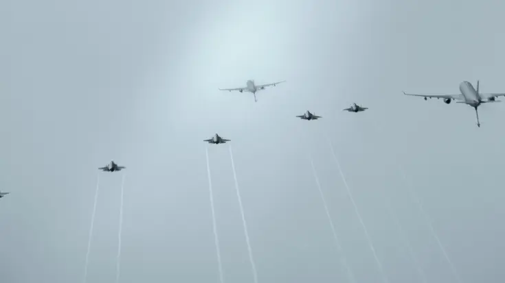 Bovenaanzicht van twee A330 MRTT’s en vijf F-35’s die tegen een egaal grijs wolkendek vliegen.