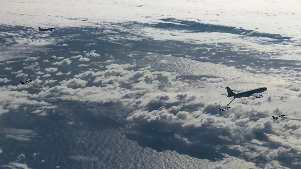 Een formatie met 2 A330 MRTT’s en 4 F-35’s, vliegend boven een bont wolkendek. 