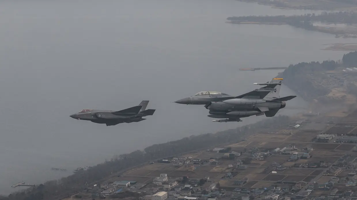 Een Nederlandse F-35 vliegt links van een Amerikaanse F-16.