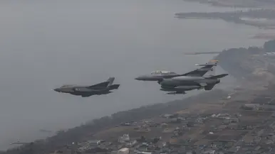 Een Nederlandse F-35 vliegt links van een Amerikaanse F-16.