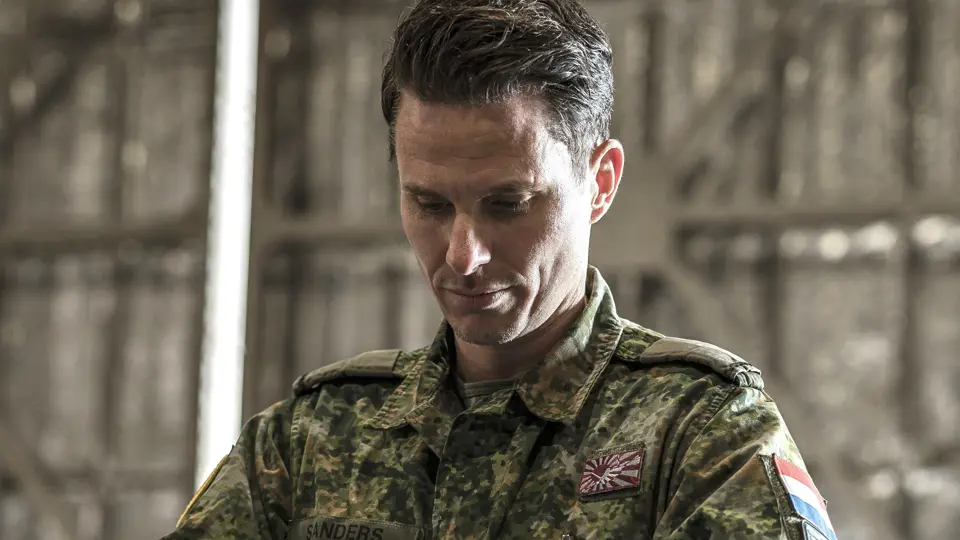 Een militair in een groen camouflagepak bekijkt een koffer die hij uit een container pakt.
