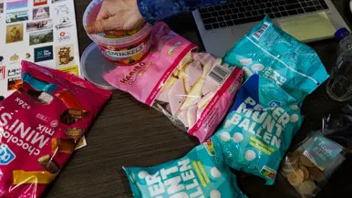 Snoepgoed en andere etenswaren op een tafel met een hand die wat winegums pakt