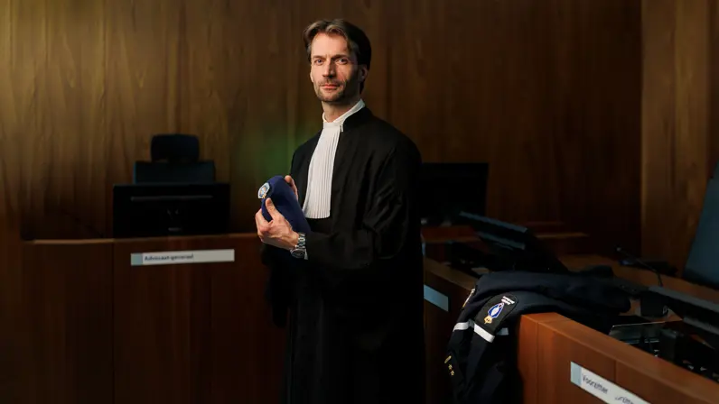 Portret van luitenant-kolonel Sébas in een toga en met baret KMar in de hand.