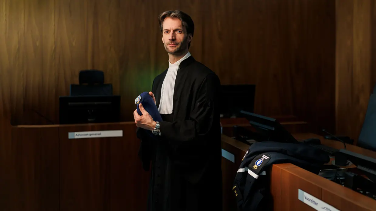 Portret van luitenant-kolonel Sébas in een toga en met baret KMar in de hand.