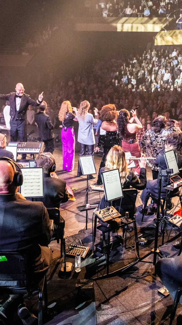 Het Luchtmachtorkest treedt op met zangers voor een volle zaal.