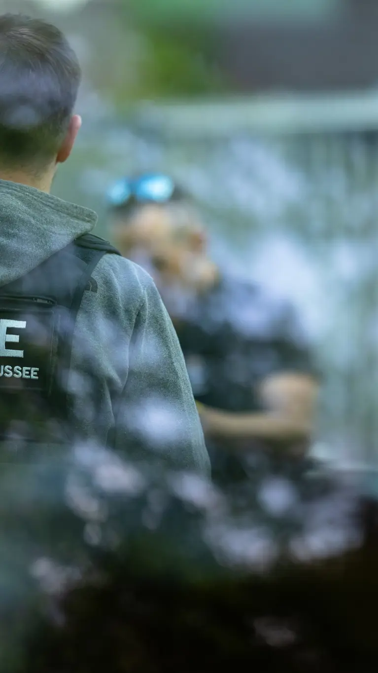 Een marechaussee in burger met een KMar-vest aan. 