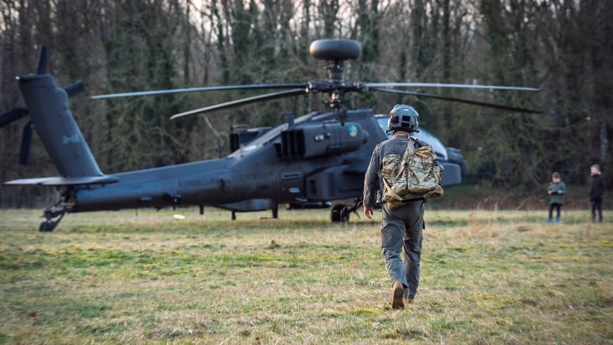 Een piloot loopt naar een Apache die aan de grond staat.