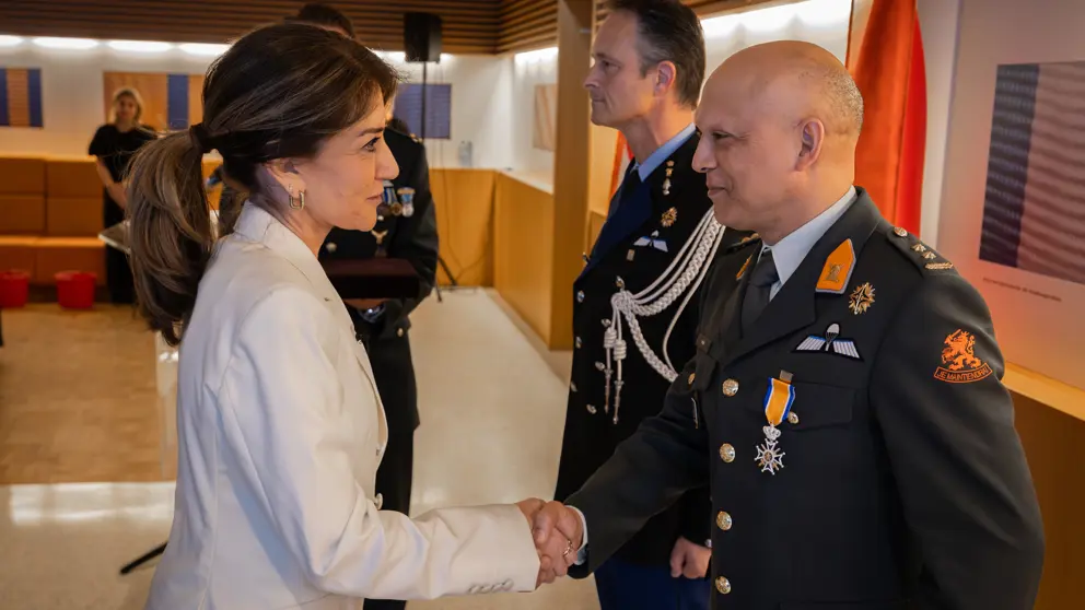 Minister van Defensie schudt de hand van gedecoreerden.