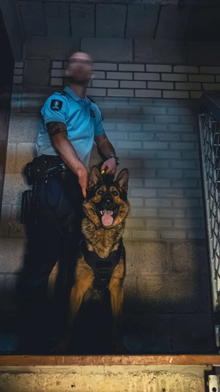Een marechaussee met zijn hond, boven aan de trap.