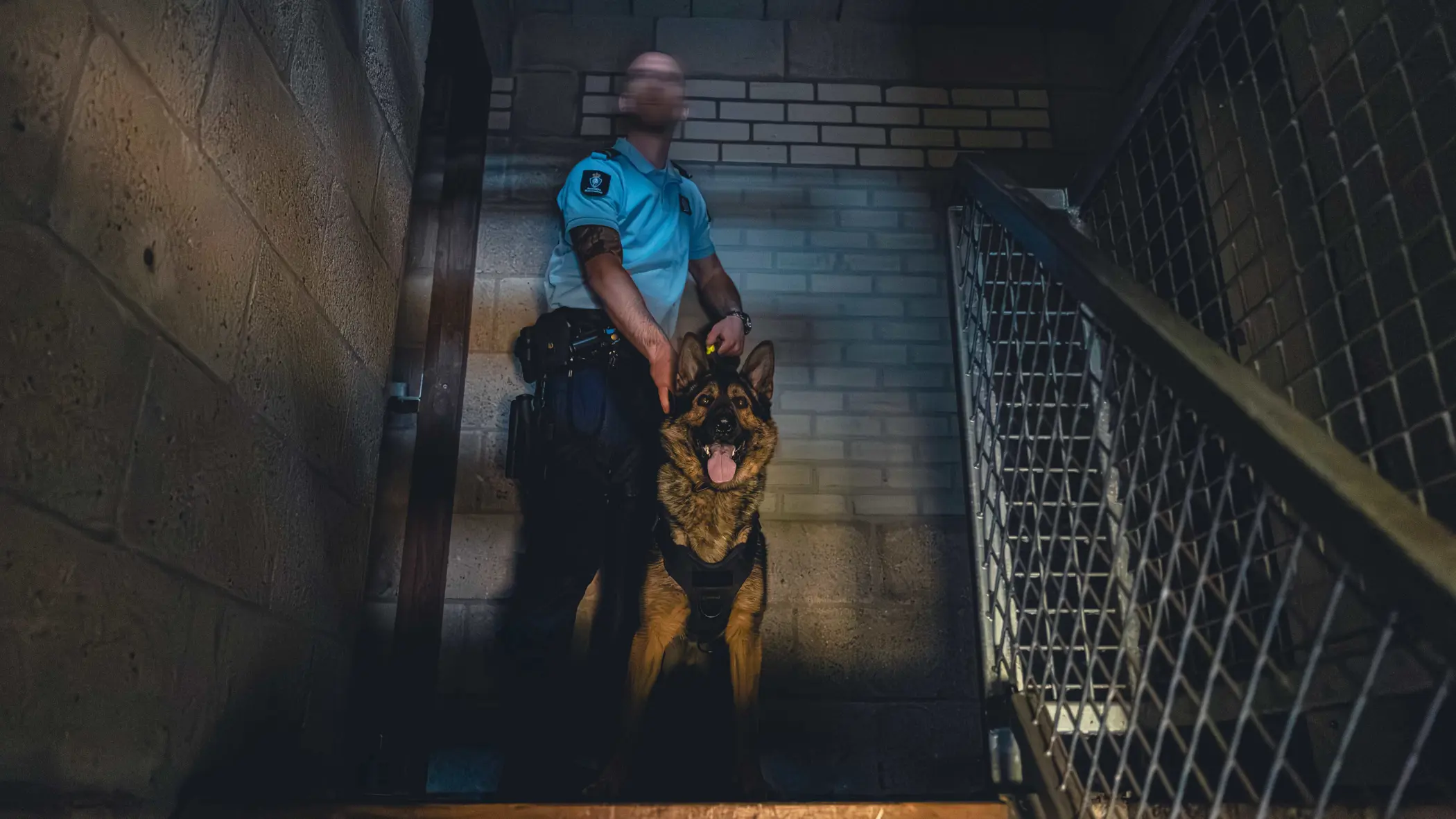 Een marechaussee met zijn hond, boven aan de trap.