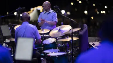 Dirigent klapt voor de drummer van het orkest. 