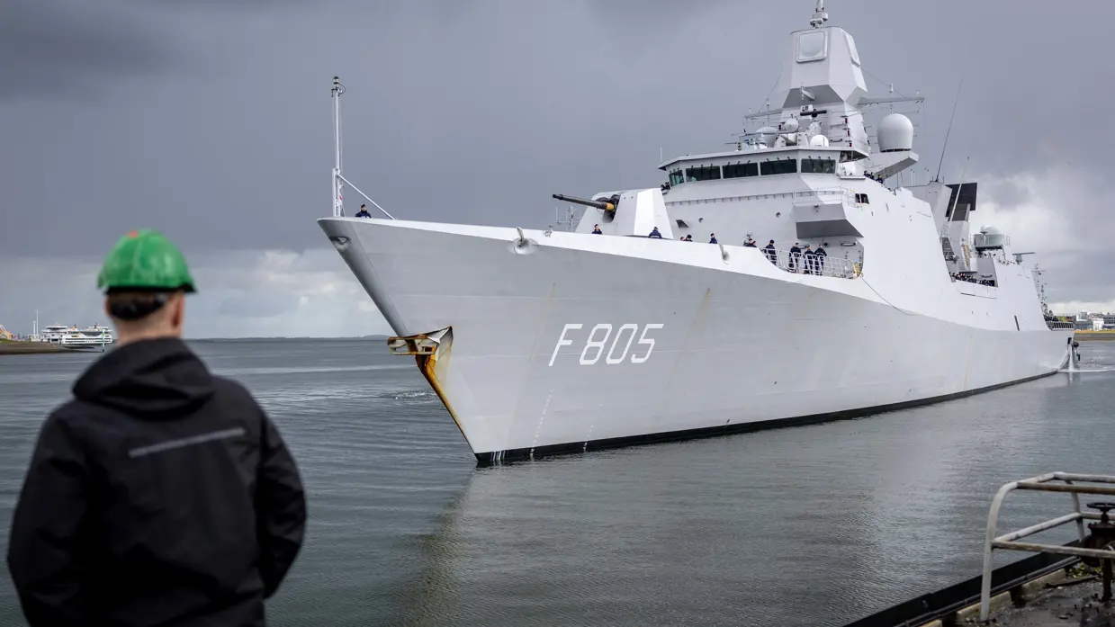 Linkerfoto: twee sleepboten escorteren de Evertsen. Rechterfoto: een marineman hoe de Evertsen richting de kade vaart. 