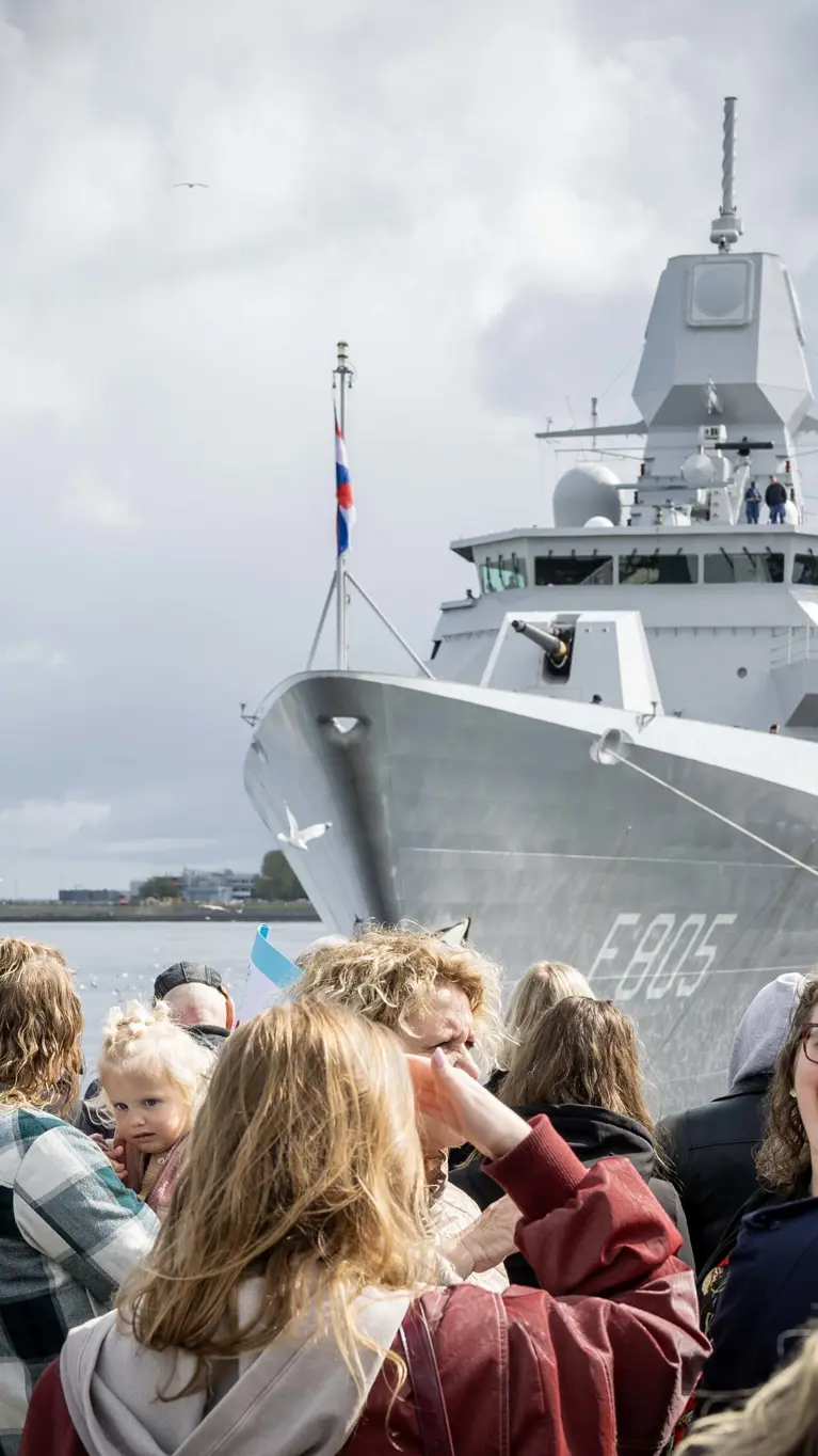 Een kade vol mensen wacht op de terugkeer van het fregat dat binnenvaart.