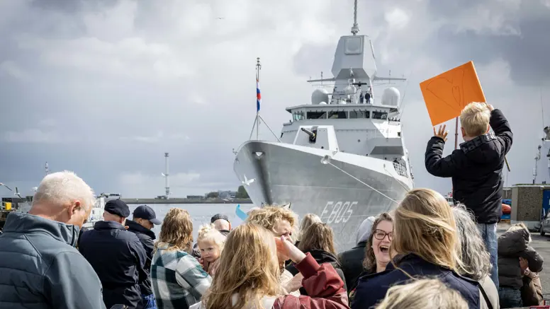 Een kade vol mensen wacht op de terugkeer van het fregat dat binnenvaart.