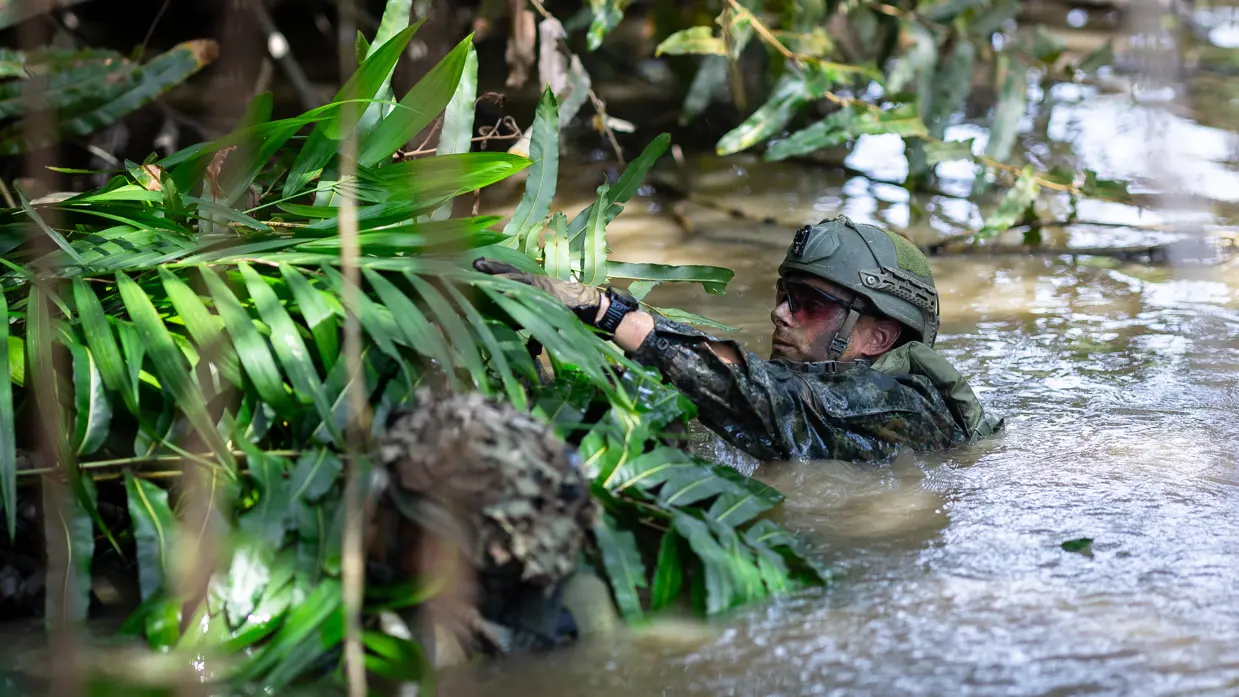 Mariniers houden een drijfpakket in de rivier vast   Marinier legt takken op het drijfpakket 