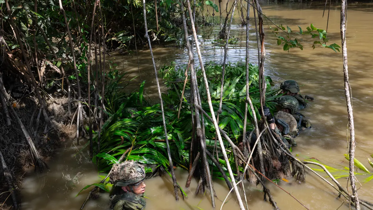 Mariniers houden een drijfpakket in de rivier vast   Marinier legt takken op het drijfpakket 
