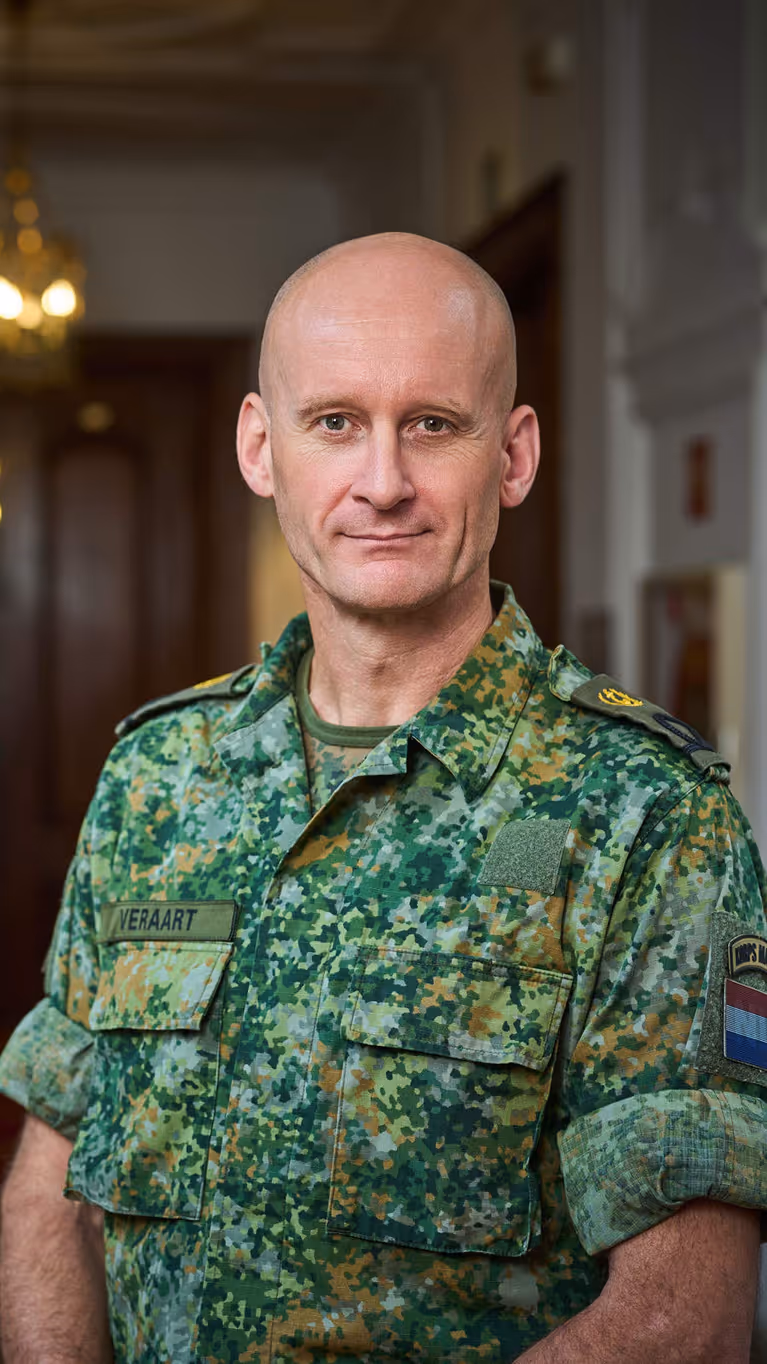 Militair in uniform staat in statige gang ministerie.