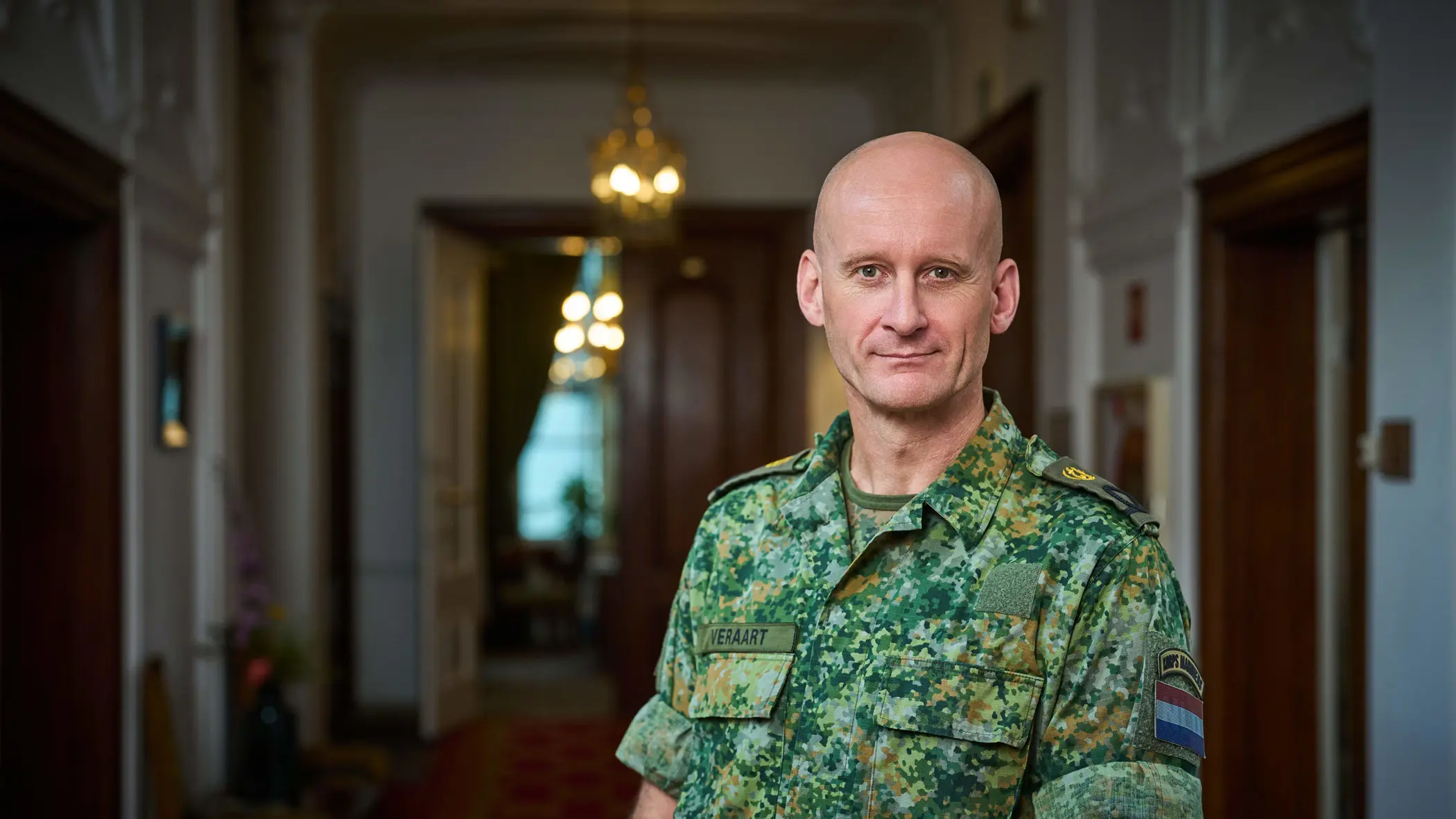Militair in uniform staat in statige gang ministerie.