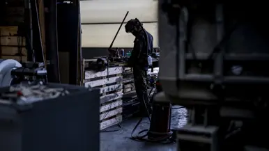 Een monteur steekt een stuk gereedschap in een motorruimte.