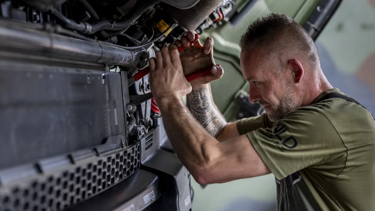 Een militair is aan het sleutelen bij het luchtafweersysteem.