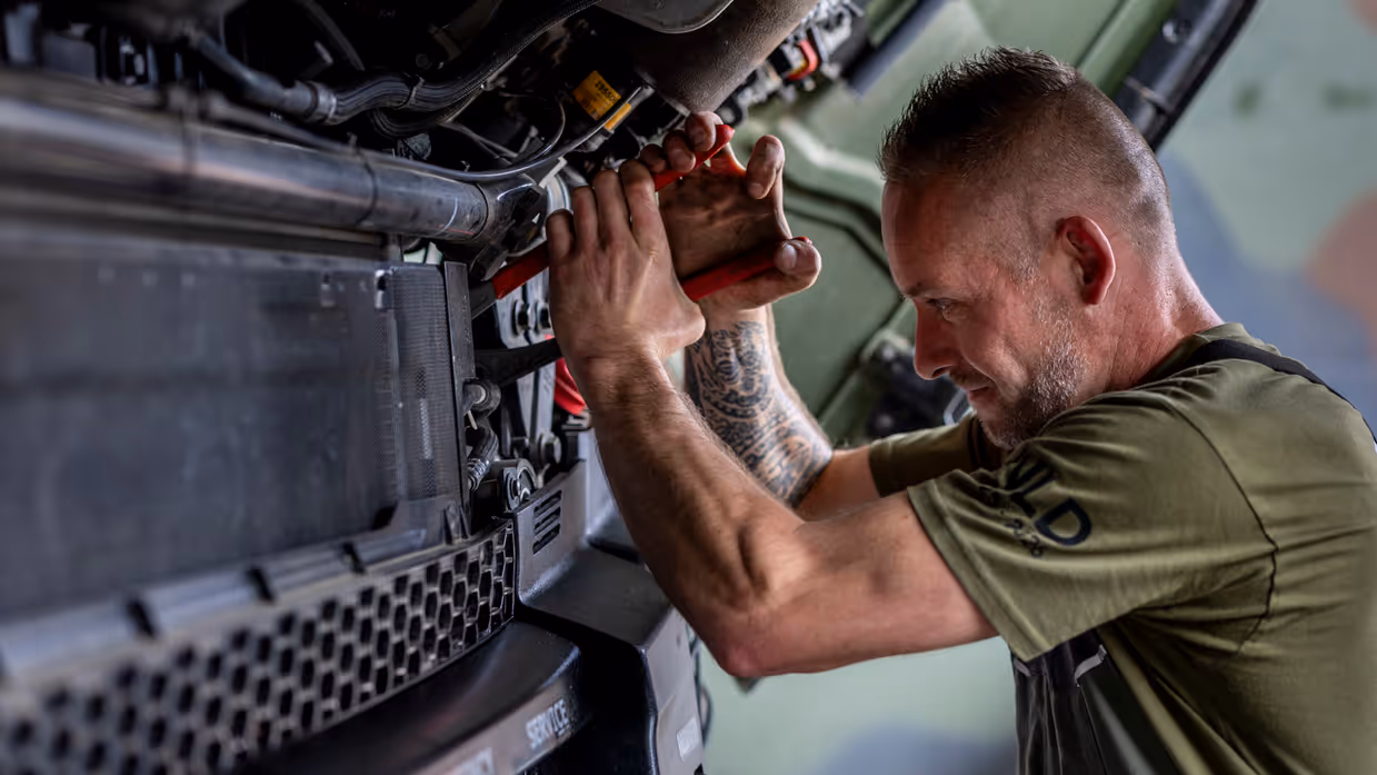 Een militair is aan het sleutelen bij het luchtafweersysteem.