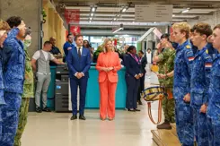Leerlingen salueren voor de voorzitter van het bestuur en de staatssecretaris.