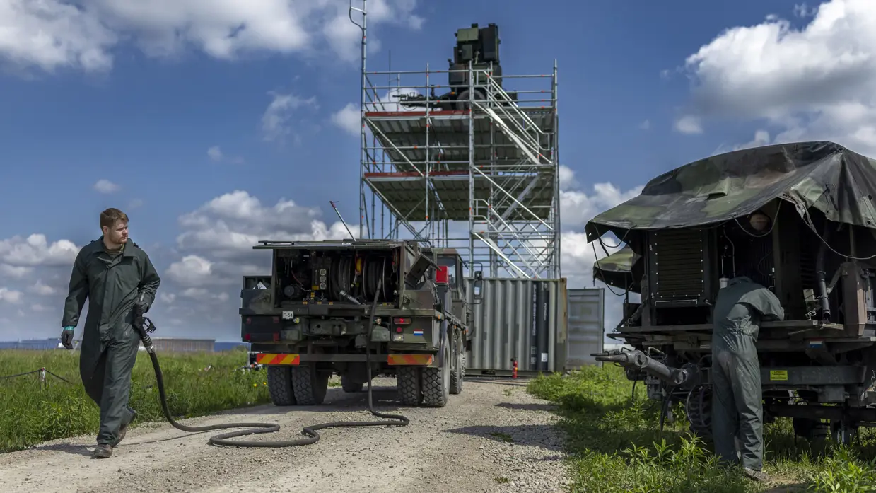 Een groep militairen is het luchtafweersysteem aan het uitladen uit trucks.
