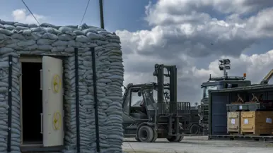 Op de linkerfoto rijdt een vorkheftruck naar een container. Op de rechterfoto zijn militairen bezig met een radarsysteem.