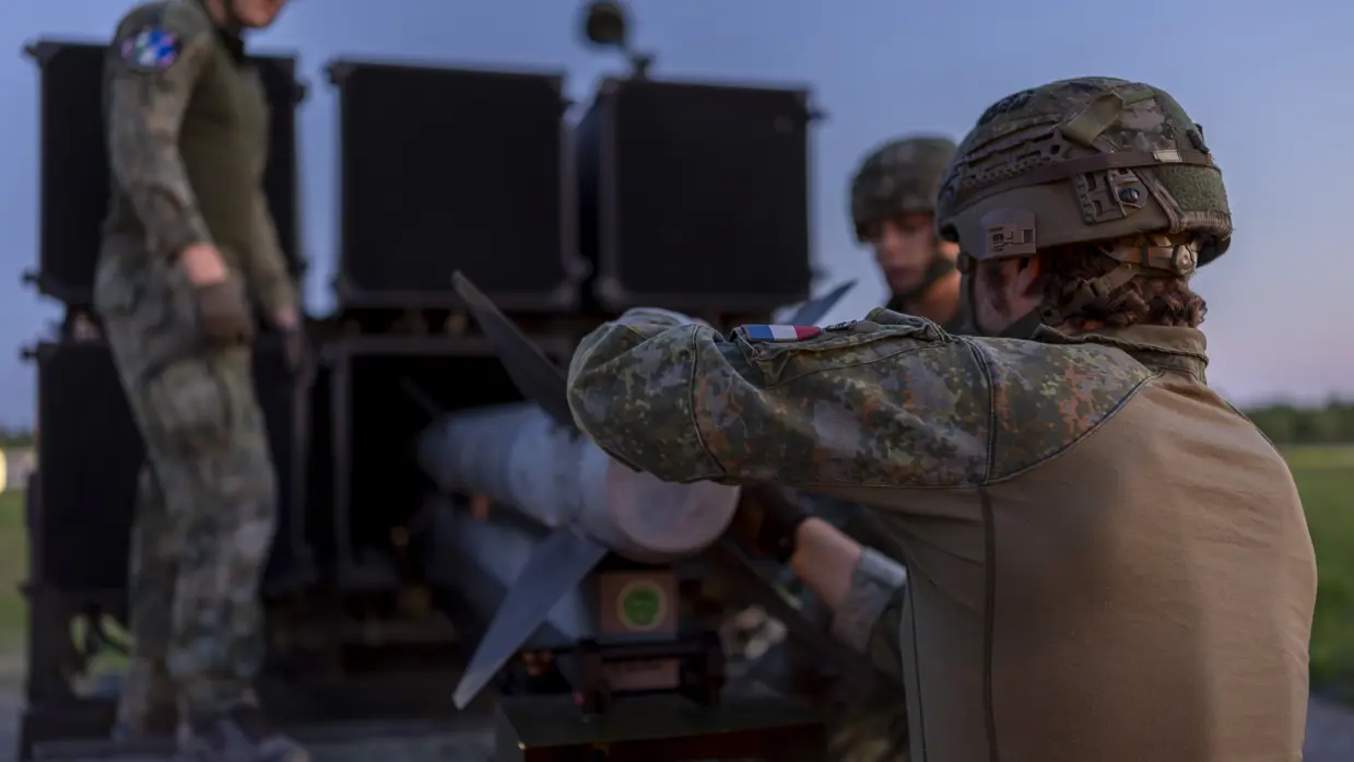 Drie militairen laden een raket in het luchtafweersysteem.