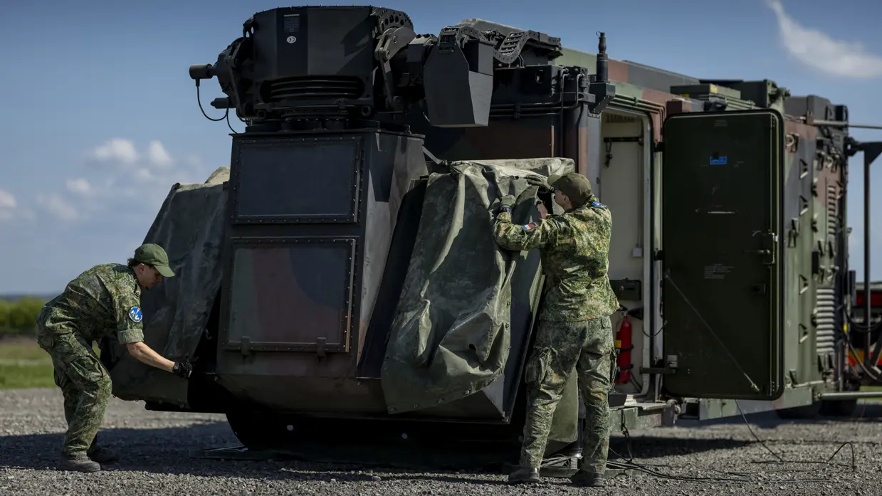 Twee militairen trekken het zeil van het luchtafweersysteem af.