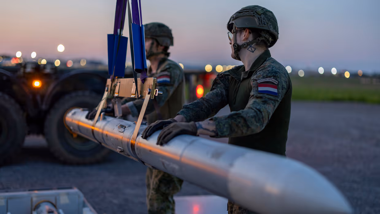 Twee militairen vervoeren met een kabel een raket.