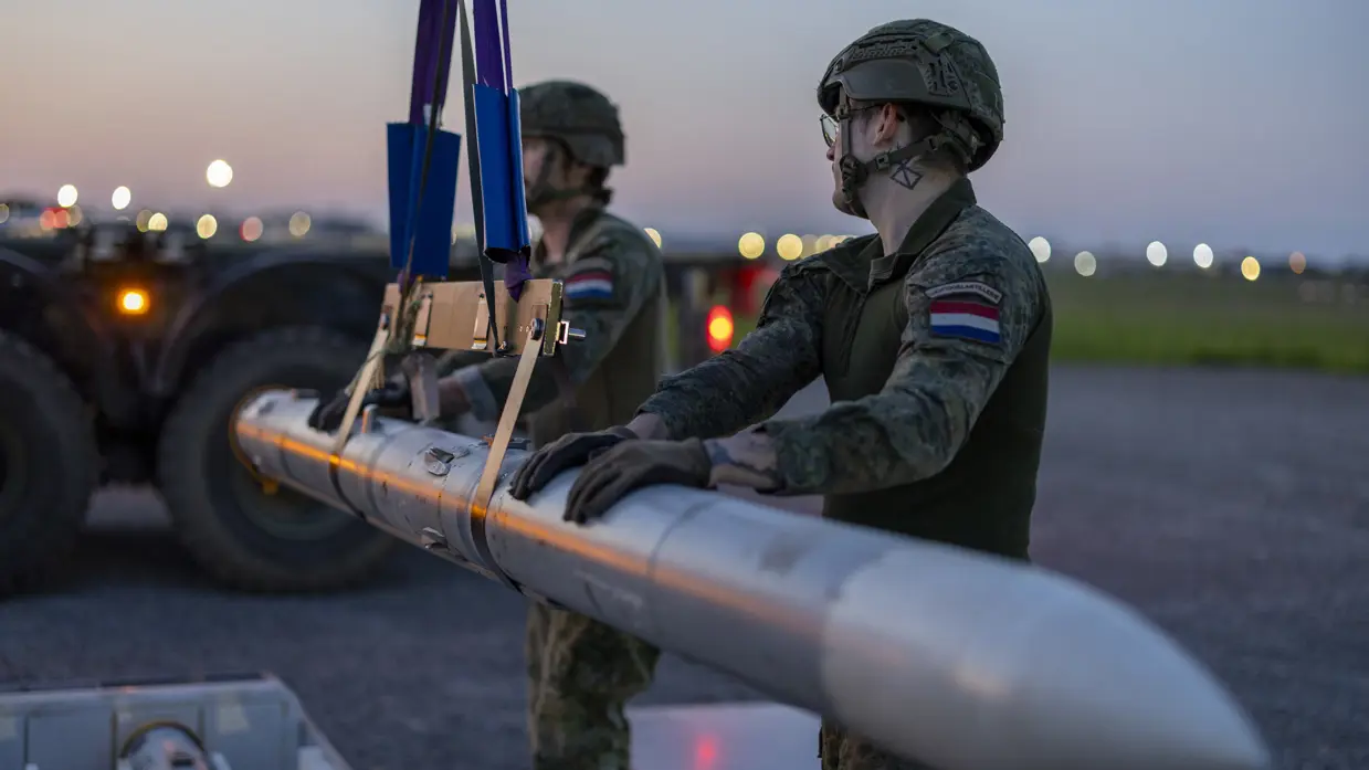 Twee militairen vervoeren met een kabel een raket.